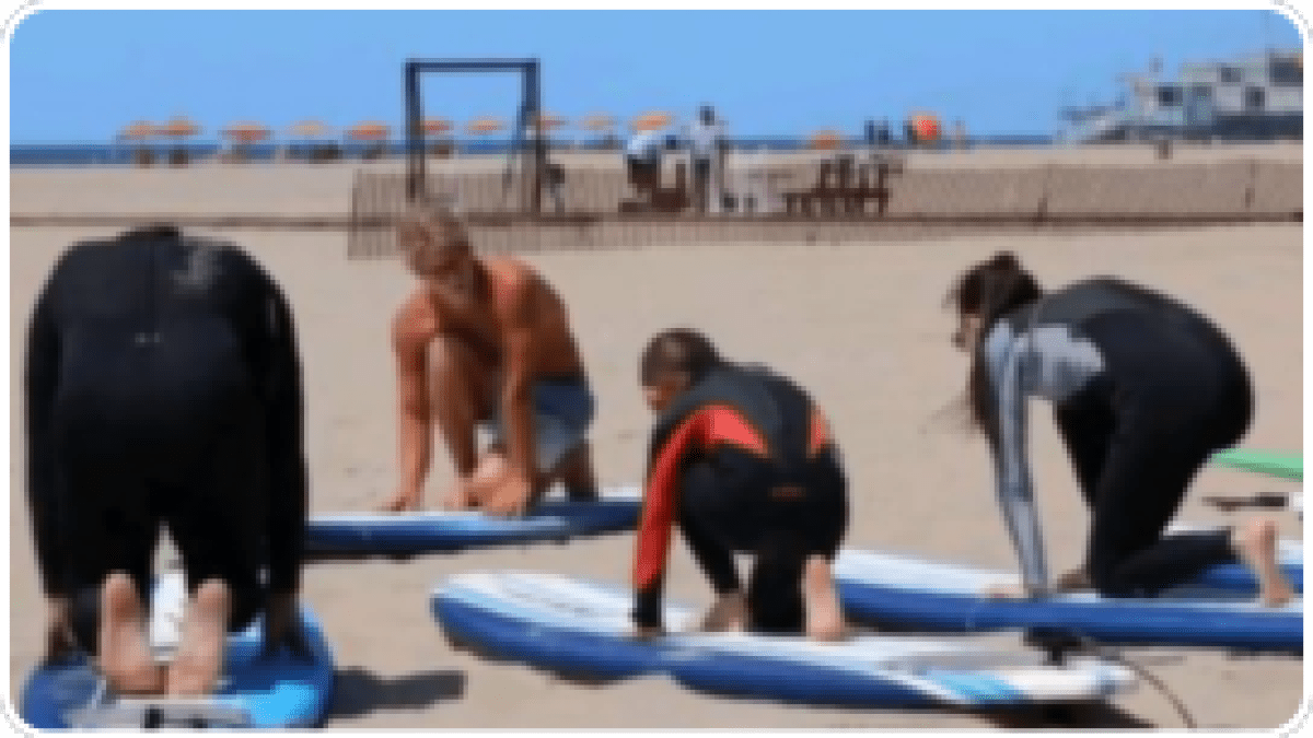 Four people practicing on surfboards on the beach.